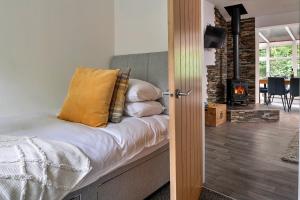 1 dormitorio con cama con almohadas y chimenea en Finest Retreats - Nant Cottage, en Llangelynin