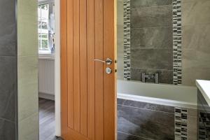 a bathroom with a wooden door and a bath tub at Finest Retreats - Nant Cottage in Llangelynin