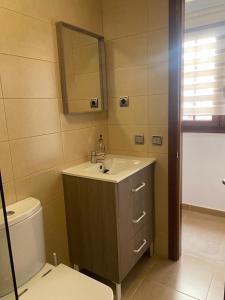 ein Badezimmer mit einem Waschbecken, einem WC und einem Spiegel in der Unterkunft Las Olas in Puerto del Rosario