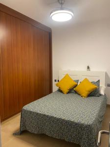 ein Schlafzimmer mit einem Bett mit gelben Kissen darauf in der Unterkunft Las Olas in Puerto del Rosario