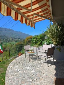 a patio with a table and chairs under an umbrella at La Casa di Emy in Solto Collina