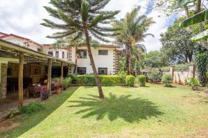 una casa con una palmera en el patio en GIGIRI DRIVE::2BR EXQUISITELY FURNISHED PENTHOUSE en Nairobi