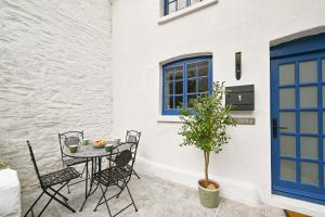 un patio con tavolo, sedie e un albero di 1 Bake Cottage Serenity - Premium Coastal Retreat in Looe, Cornwall a Looe