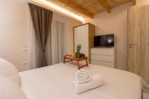Schlafzimmer mit einem Bett, einem TV und Handtüchern in der Unterkunft RELAXING POOL HOUSE IN LAGONISI 1 in Kalívia Thorikoú