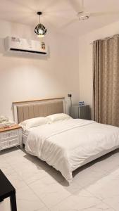 - une chambre avec un grand lit blanc et un bureau dans l'établissement Tiwi Pearl, à Sour