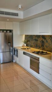 a kitchen with white cabinets and a stainless steel refrigerator at Harbour-view Waterfront Apartment in Darwin
