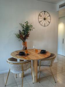 a table with two chairs and a clock on the wall at Harbour-view Waterfront Apartment in Darwin