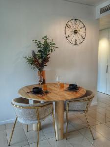 a table with two chairs and a clock on the wall at Wharf-view Waterfront Apartment in Darwin