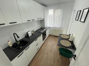 een keuken met witte kasten en een zwart aanrecht bij Apartament Central in Onești