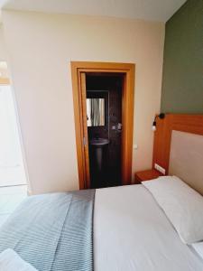 1 dormitorio con 1 cama y puerta al baño en ANDOYA pansiyon en Bodrum