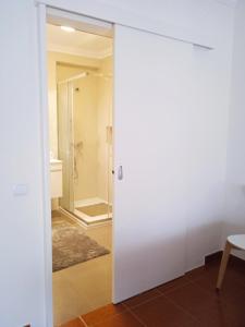 uma casa de banho com uma porta de vidro que leva a um chuveiro em Casa Senhor dos Passos na Nazaré