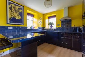 cocina con paredes amarillas y encimera azul en Lowtown Cottage en Brampton