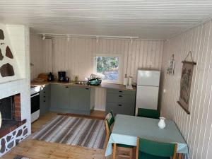 eine Küche mit einem Tisch und einem Kühlschrank in der Unterkunft Bastukleven, stuga i Hamnsundets skärgårds idyll in Saltvik