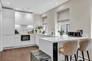 a kitchen with white cabinets and a counter with stools at Be London - Chancery Lane Apartments in London