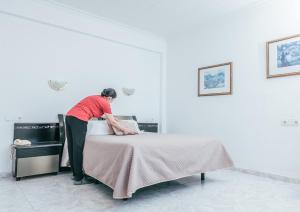 Una mujer está haciendo una cama en una habitación en Hotel Duc de Vendôme, en Vinarós
