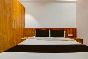 OYO Hotel Delight Stay في إندوري: غرفة نوم مع سرير مع اللوح الأمامي الخشبي