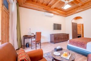 a hotel room with a bed and a desk with a table at Ezzenza Swarg by Beas Golf Resort - Devlok Manali in Baragrān