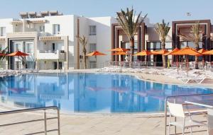 een groot zwembad met stoelen en oranje parasols bij App S1 à l'hôtel Andalucia Beach in Bizerte