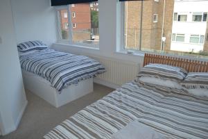 two beds in a room with a window at Nice 3 Bedroom House Wimbledon in London