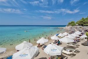 Una playa con sombrillas blancas y gente en el agua. en Sirius Villa Nikiti Sithonia Halkidiki 3 bedrooms 8 guests, en Skála Nikíta
