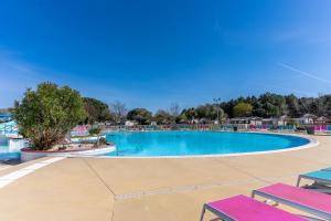 una piscina in un resort con panchine e alberi di Mobilhome a La reserve a Gastes