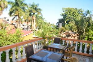 a balcony with a table and chairs and palm trees at Lakeshore Bed and Breakfast in Entebbe