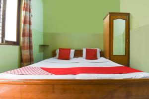 a bedroom with a bed with red and white pillows at Hotel Poojan Heritage in Haridwār