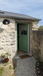 a green door on a stone building with aphalt at La Bonne du Curé in Annoville