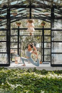 a woman doing a yoga pose in a room with windows at Finca Serena Mallorca, Small Luxury Hotels in Montuiri