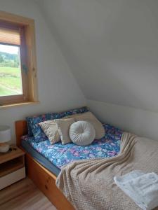 a bed with pillows and a window in a room at Domek Górski Klimat in Białka Tatrzanska