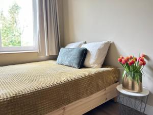 Una cama con un jarrón de tulipanes sentado junto a una ventana en Lovely Spacious Apartment en Zandvoort