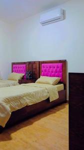 a bedroom with two beds with pink head boards at شقة فاخرة واسعة في شارع المدينة المنورة in Umm Uthainah