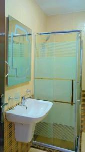 a bathroom with a sink and a glass shower at شقة فاخرة واسعة في شارع المدينة المنورة in Umm Uthainah
