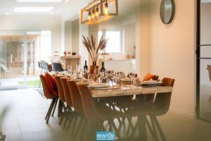 een lange tafel in een kamer met stoelen en een tafel bij Casa Diva – renovated house for 12 in Blankenberge in Blankenberge