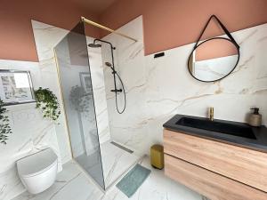 uma casa de banho com um chuveiro, um WC e um lavatório. em Lovely Spacious Apartment em Zandvoort