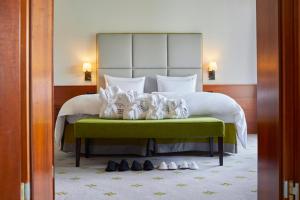 una habitación de hotel con una cama con zapatos en el suelo en Kempinski Hotel Frankfurt Gravenbruch, en Gravenbruch