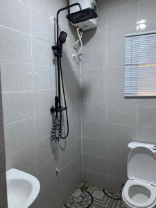 a bathroom with a toilet and a hair dryer on the wall at Garden View Holiday Cottage in Abakaliki