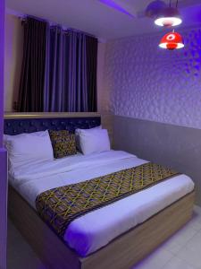 a bedroom with a large bed with purple lighting at Garden View Holiday Cottage in Abakaliki