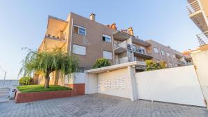 an apartment building with a garage and a tree at São Felix Seaview Retreat by LovelyStay in São Félix da Marinha