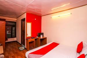 a bedroom with a bed and a desk with a red wall at OYO Flagship View Point Resort in Nainital