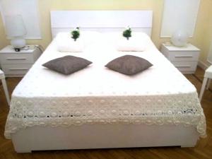 una camera da letto con un letto bianco con lenzuola e cuscini bianchi di Un Giardino a Due Passi dal Mare a La Spezia