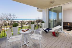里米尼的住宿－里米尼朗格馬雷美居酒店，阳台设有带白色椅子和桌子的庭院。