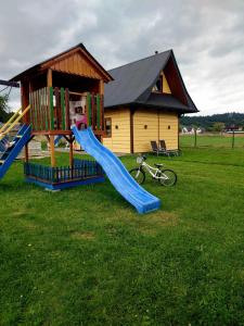 un parque infantil con un tobogán frente a una casa en Domki Górski Klimat, en Białka Tatrzanska