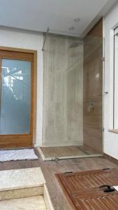 een douche met een glazen deur in een kamer bij Luxury house with swimming pool in Ben Arous