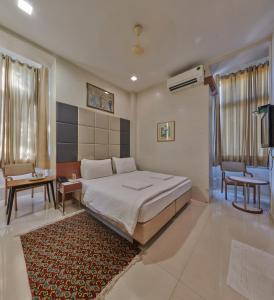 a bedroom with a large bed and a rug at Elphinstone Hotel in Mumbai