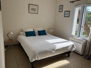 a bedroom with a large bed with blue pillows at Mon Dada 150m de la plage, climatisee in Saint-Georges-dʼOléron