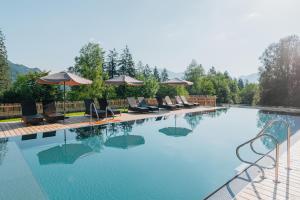 una gran piscina con sillas y sombrillas en Wellness Aparthotel "Lechlife" incl Infinity Pool - 400m zum Lift, en Reutte