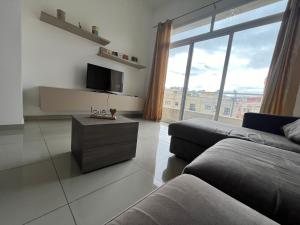 a living room with a couch and a tv at Swieqi Centre - Perfectly Located in Tal-Għoqod