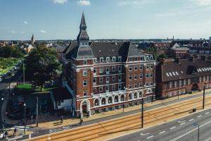 a large brick building with a tower on a street at Milling Hotel Plaza in Odense