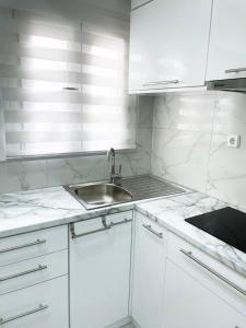 a white kitchen with a sink and white cabinets at Apartment in the center of Athens in Athens